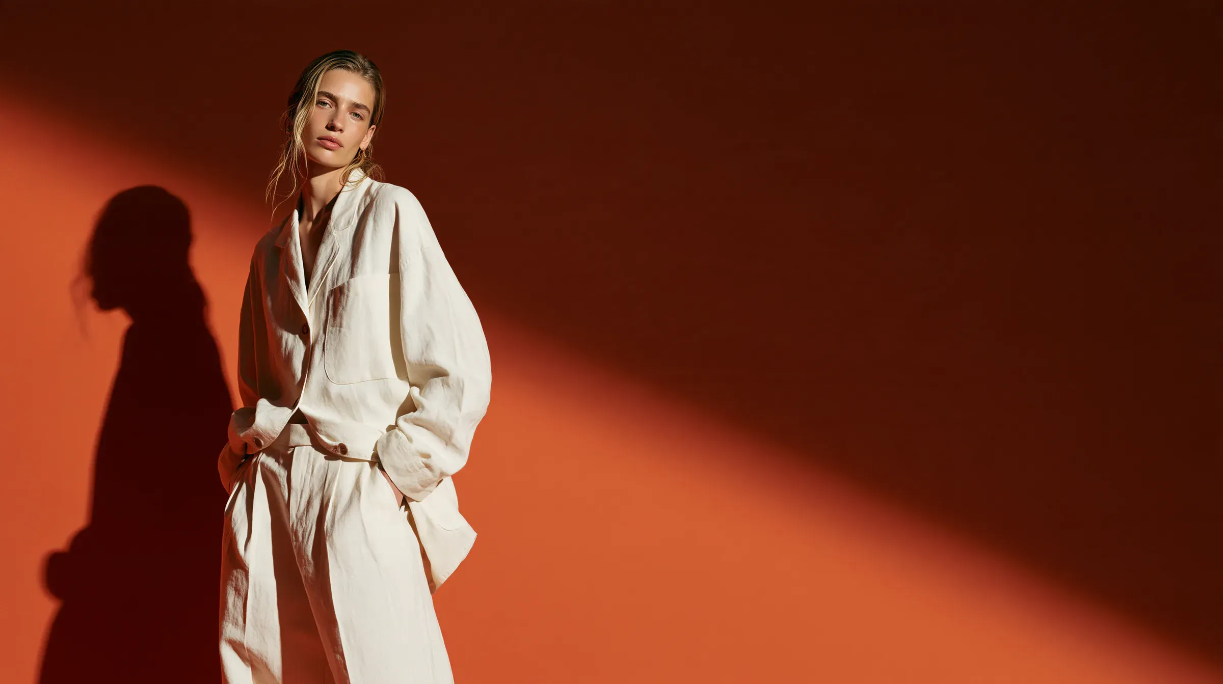 Modelo con traje de lino crudo frente a un muro terracota